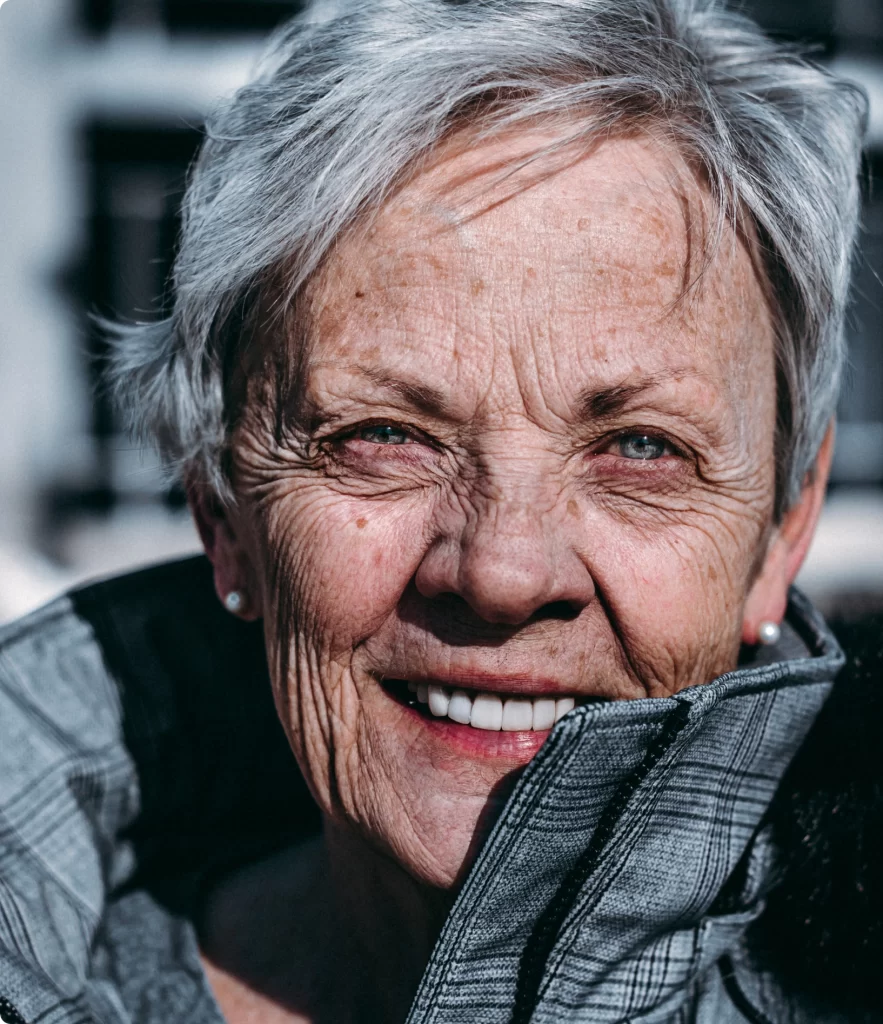 Beautiful old woman in close up with grey short hair freckles and shiny white teeth she feels rejuvitaned after her HBOT treatment with HBOT4LIFE.